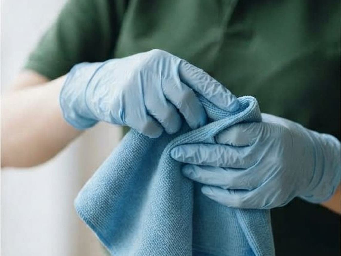 Mains gantées pliant une microfibre bleue, gros plan